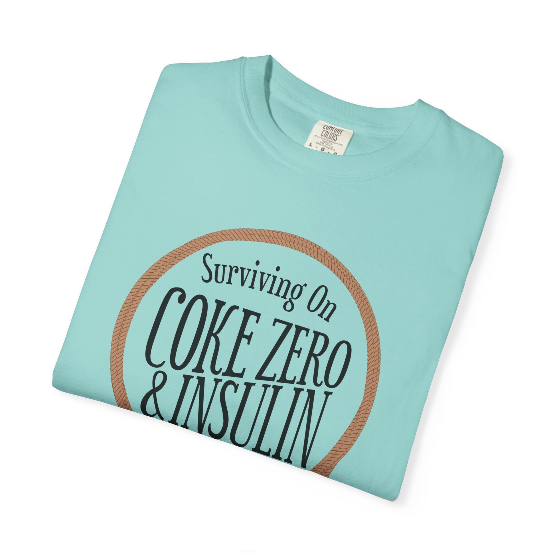 Surviving on Coke Zero Western Diabetes Tshirt featuring curled rope design and bold statement on a turquoise garment.