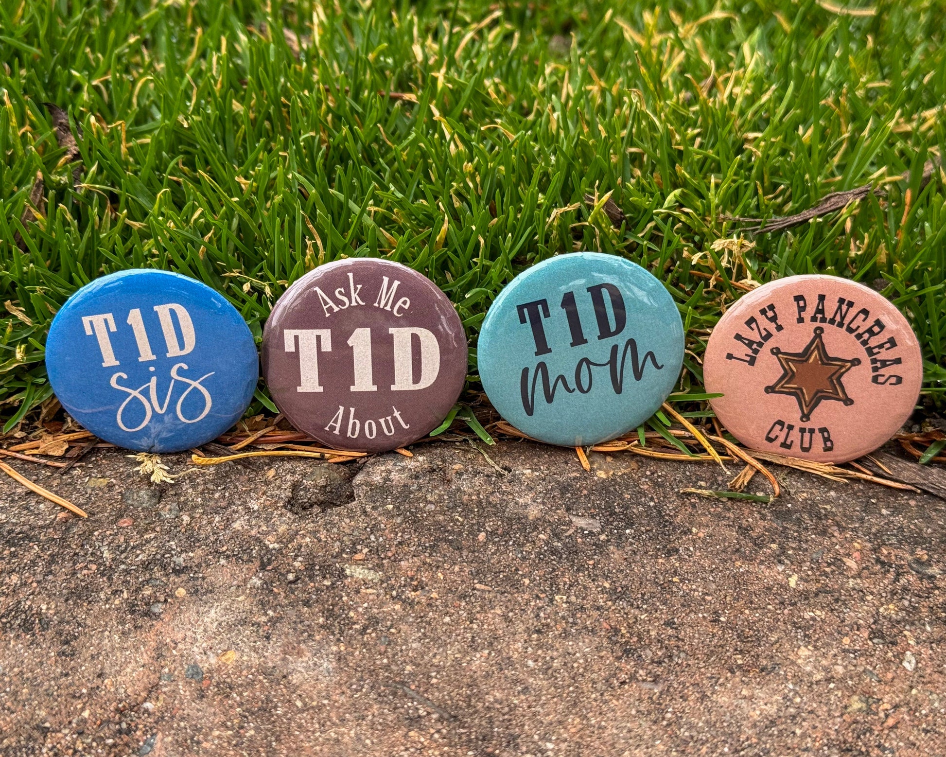 Four diabetes awareness buttons with text and designs on a grassy background